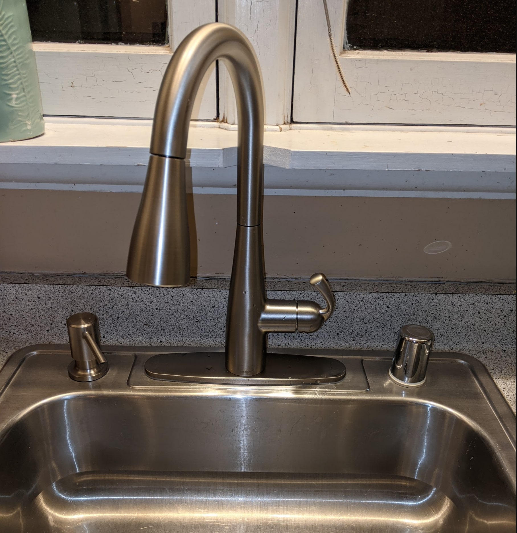 A shiny new kitchen faucet installed in an old kitchen.