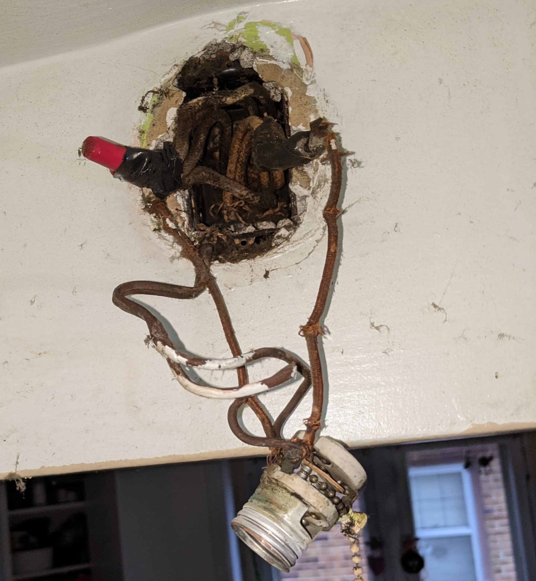An absolute mess of an electrical box containing 10 wires with crumbling insulation